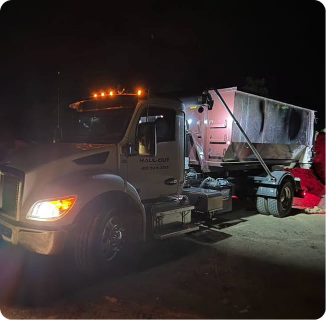 Haul-out truck with dumpster at night.